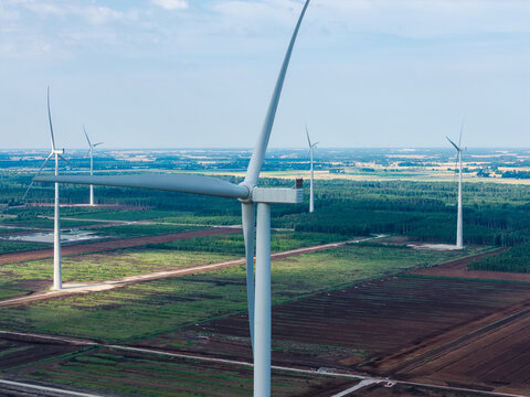 Aerial view of wind turbines at the Kaigu Bog wind farm, featuring tall structures set against a vast landscape of peatlands and forests in Latvia.