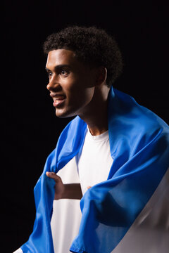 African man holding blue draped fabric over shoulders and wearing white T-shirt in studio