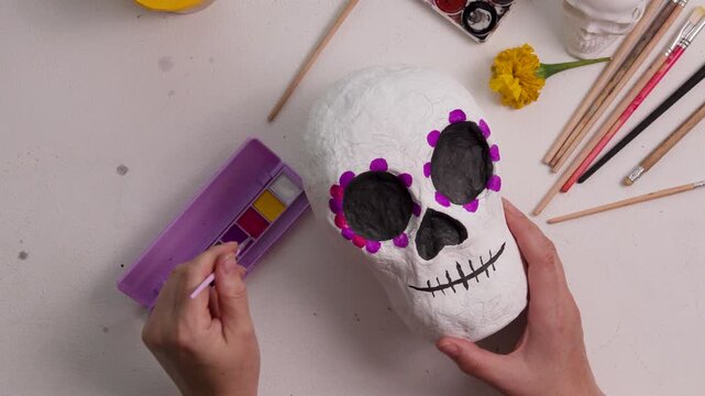 Handmade papier-mache calavera skull painted with pink floral accents for Dia de los Muertos decor