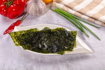 Nori seaweed sheets on white plate with fresh vegetables and kitchen towel © Andrei Starostin
