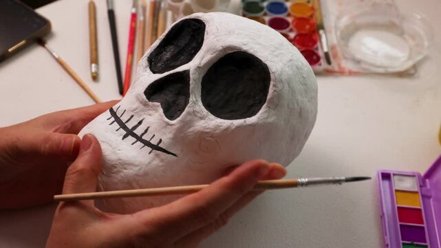 Handmade papier mache calavera skull being painted in a DIY home studio setup