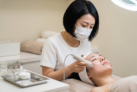 Facial treatment with skincare specialist using a handheld beauty device
