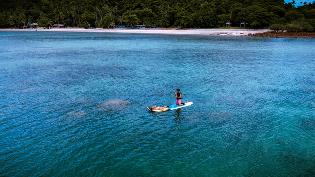 Top aerial view of Group of tourist are enjoy on water sport paddle sup-board  along at the sea under crystal clear of water in the island of summer trip