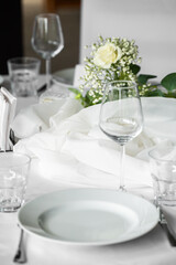 Fototapeta premium Elegant wedding table setting with white runner, plates, wine glasses, and rose centerpiece with baby's breath.