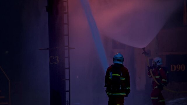 Firefighters wearing protective gear are using hoses to clear an oil vent during an outdoor fire drill