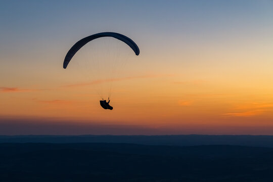Paraglider silhouetted against a spectacular sunset, representing freedom, adventure and escape. Atmospheric image for travel, outdoor lifestyle, tourism and the dream of flying.