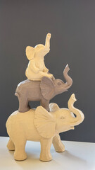 Decorative elephant figurines stacked in a playful arrangement against a dark background, neutral home decor with symbolic animal sculptures. © VerraDesigns