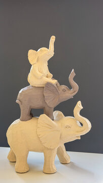 Decorative elephant figurines stacked in a playful arrangement against a dark background, neutral home decor with symbolic animal sculptures.