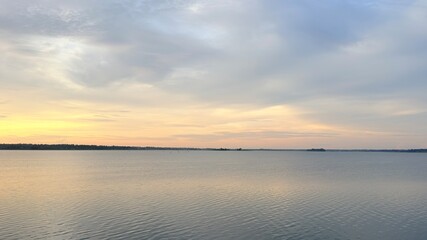 Obraz premium Serene Golden Sunset Over Calm Lake Water with Cloudy Sky Horizon