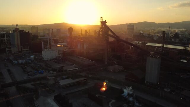 Aerial view of a steelworks with blast furnace at sunset and molten slag being poured