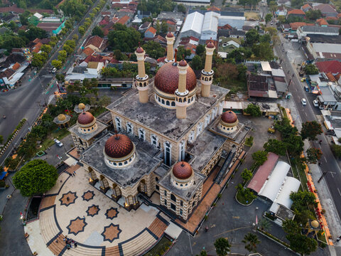 Aerial view of Al Aqsha Great Mosque Klaten with its prominent red domes and minarets, surrounded by urban streets and trees in Klaten, Central Java, Indonesia.