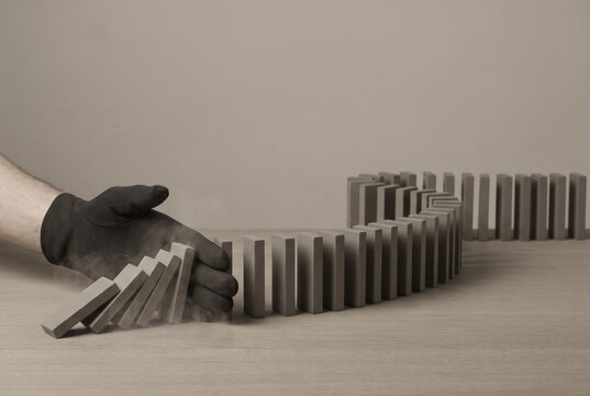 Domino Risk Management Hand Stopping Chain Reaction