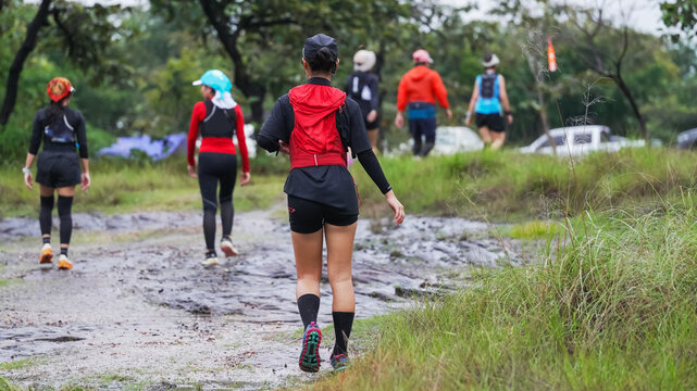 Group of runners hiking along a muddy trail through a lush forest