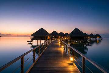 Obraz premium Overwater bungalow resort boardwalk at sunset in a tropical lagoon