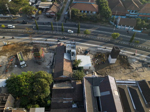 Aerial view of the construction of the Solo-Yogyakarta Toll Road with concrete pillars, heavy machinery, and workers on site, Kecamatan Depok, Daerah Istimewa Yogya, Indonesia.