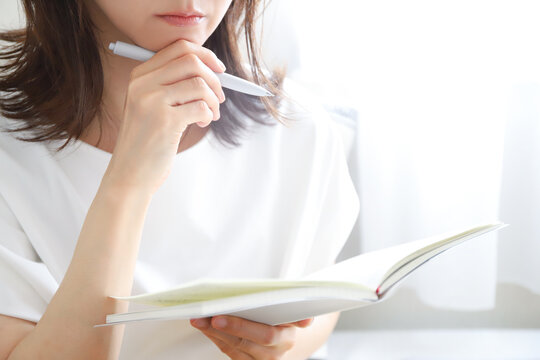 手帳を見ながら考え込む女性