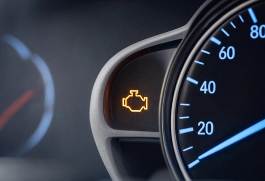 Orange check engine warning light glowing on modern car dashboard indicates vehicle malfunction, engine repair, maintenance, diagnostics, automotive service, and mechanical problems.
