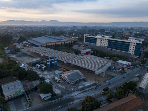 Aerial view of the construction of the Solo-Yogyakarta Toll Road featuring concrete pillars and heavy machinery amidst urban development in Kecamatan Depok, Daerah Istimewa Yogya, Indonesia.