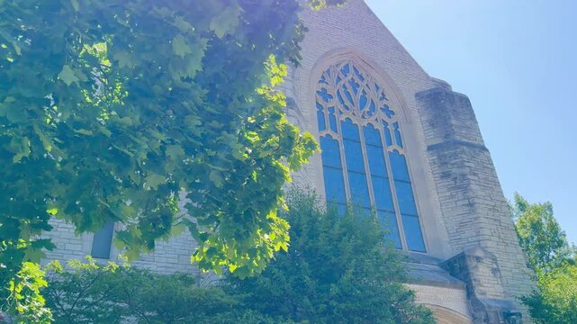 Horizontal 4K video of a beautiful Gothic church illuminated by warm sunlight, partially framed by trees. Atmospheric architecture, peaceful scenery, and timeless historic charm, perfect for travel