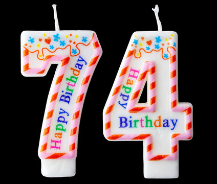 Number seventy four shaped birthday candle with colorful sprinkles and Happy Birthday text isolated on a black background