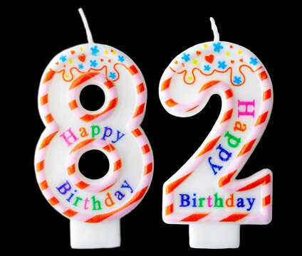 Number eighty two shaped birthday candle with colorful sprinkles and Happy Birthday text isolated on a black background