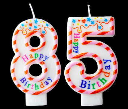 Number eighty five shaped birthday candle with colorful sprinkles and Happy Birthday text isolated on a black background