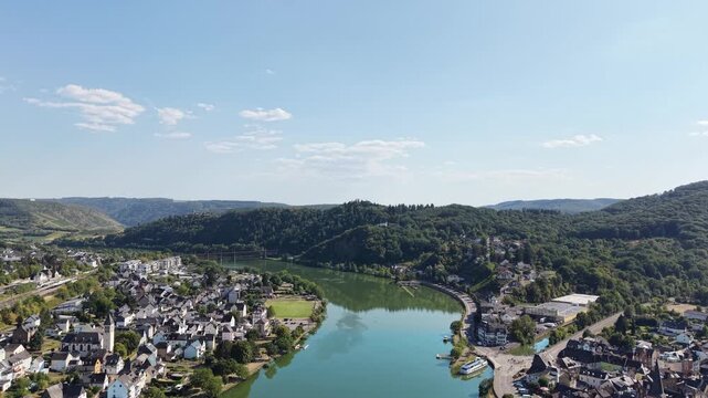 Aerial drone view of Bullay on the Moselle River in Rhineland-Palatinate, Germany, featuring the riverside village, church, river bend and surrounding forested hills in the scenic Moselle Valley.