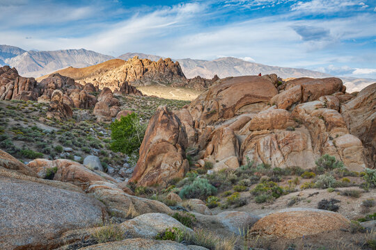 Beautiful wide panorama of a rocky desert landscape with a tiny hiker on top of a rock