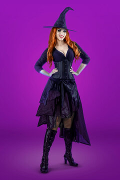 Witch on Halloween. Female wizard fairy character for All Saints' Day. Fantasy gothic red-haired Vampire girl in black dress. Enchantress dressed in carnival costume