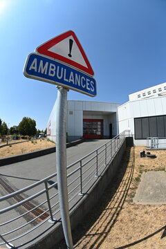 signal&eacute;tique pour l'entr&eacute;e des ambulances &agrave; l'h&ocirc;pital. Panneau routier et lettres blanches peintes sur la route en goudron. Au fond le mot Urgences est peint sur un mur blanc avec un fond rouge vif