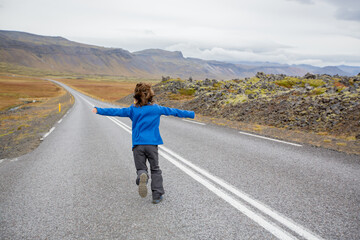 Fototapeta premium Child, playing on a road near non active vulcano in Snaefellsjokull National Park, Iceland autumntime
