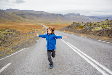 Fototapeta premium Child, playing on a road near non active vulcano in Snaefellsjokull National Park, Iceland autumntime
