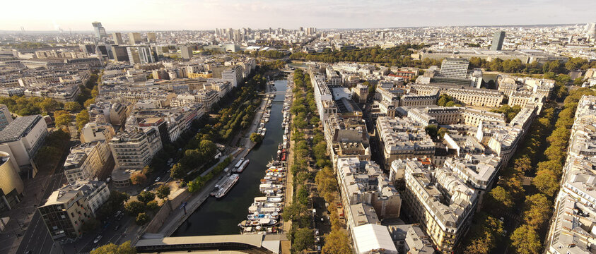 Aerial view of the Canal Saint-Martin lined with boats and historic urban architecture in Paris, Ile-de-France, France.
