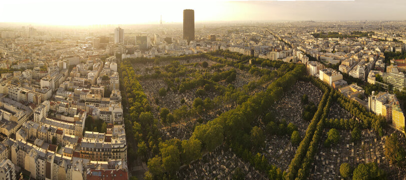 Aerial view of Montparnasse Cemetery with its dense rows of grave markers and lush trees surrounded by the urban cityscape of Paris, Ile-de-France, France.