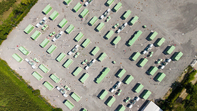 Aerial view of the BESS SERRE TAVAZZANO facility, featuring rows of green battery storage containers arranged on a gravel lot in Tavazzano con Villavesco, Lombardy, Italy.