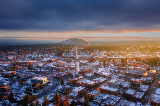 Aerial view of Pilot Butte overlooking the snow-covered city during a winter sunrise with dramatic clouds in Bend, Oregon, United States.