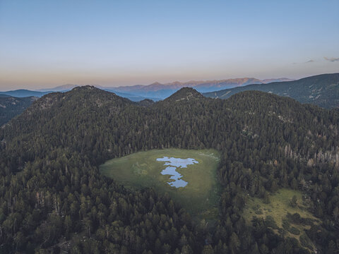 Aerial view of Le Petit Canada surrounded by dense pine forests and rolling mountains in Bolquere, Occitanie, France.
