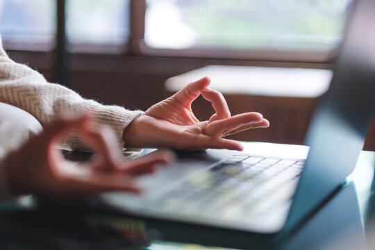 Closeup image of a woman hands in lotus pose over laptop computer for stress relief concept