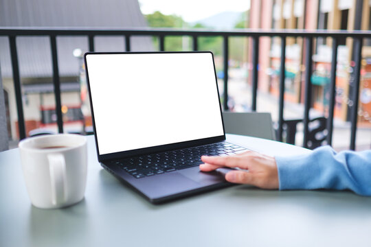 Mockup image of a woman working and touching on laptop computer touchpad with blank white desktop screen in cafe