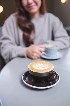 Vertical closeup image of a woman holding and drinking coffee with friend