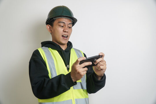 Excited Construction Worker in Hard Hat and Safety Vest Playing Mobile Game