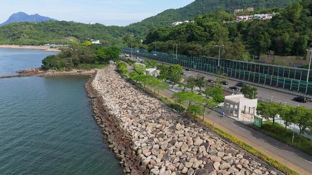 Aerial view of vehicles driving on Tolo Highway next to the scenic Tolo Harbour coastline and cycling track in Hong Kong.