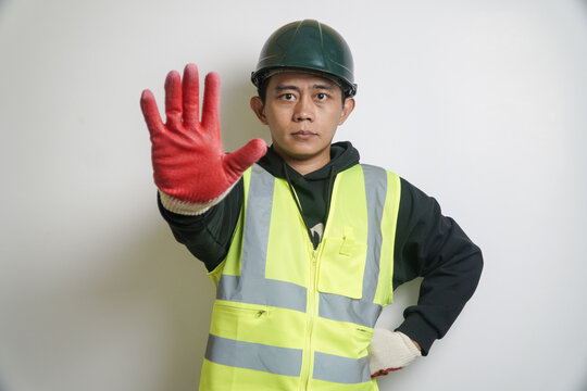 Safety Worker in Hard Hat and Vest Showing Stop Hand Gesture Seriously