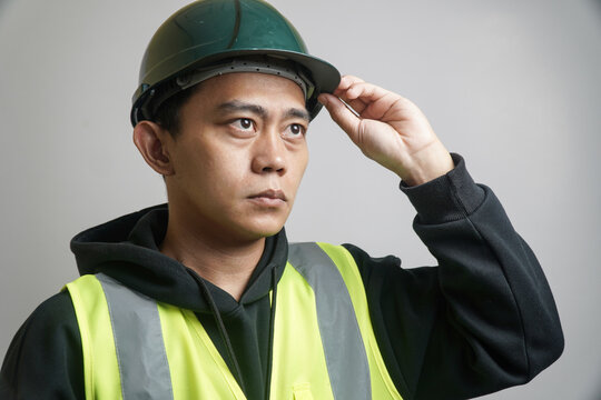 Focused Construction Worker in Green Hard Hat and High visibility Vest