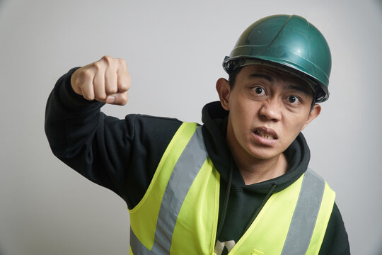 Determined Asian Construction Worker in Safety Gear Clenching Fist
