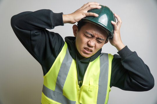 Stressed Asian Worker in Safety Vest and Hard Hat, Grimacing in Pain
