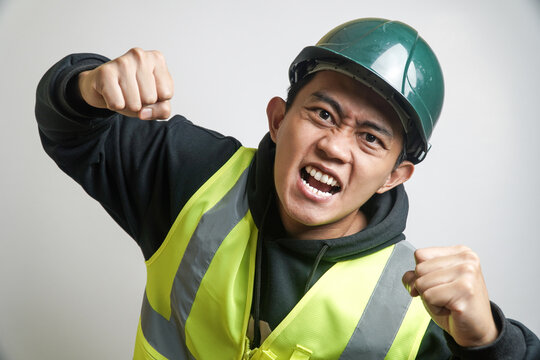 Frustrated Asian Construction Worker in Safety Vest and Hard Hat Yelling with Clenched Fists