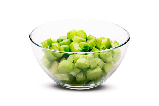 Glass bowl filled with diced green rhubarb pieces on bright white background, fresh raw ingredient with crisp texture, clean studio lighting, top view slight angle