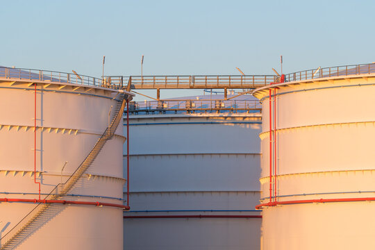 Large oil storage tanks at an industrial refinery facility. Petroleum and fuel storage reservoir tanks in a chemical production plant.
