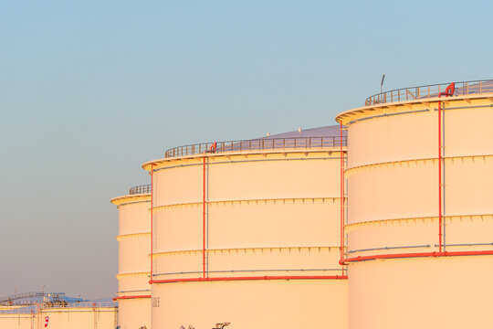Large oil storage tanks at an industrial refinery facility. Petroleum and fuel storage reservoir tanks in a chemical production plant.